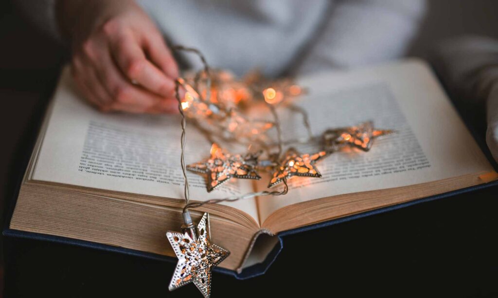 Reading a ghost story open book with Christmas fairy lights