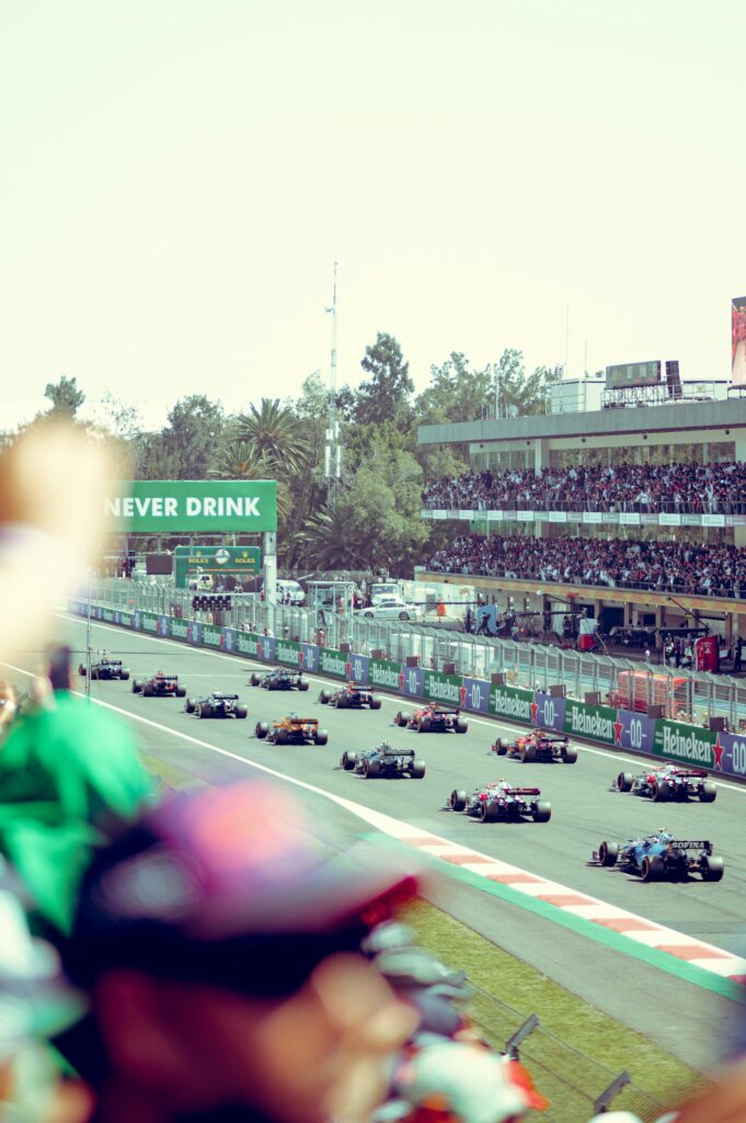 Formula 1 cars on a grid at the start of a race with crowds cheering