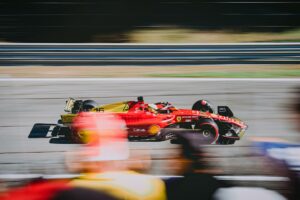 A Ferrari F1 car on a race track with blurry people in the crowd